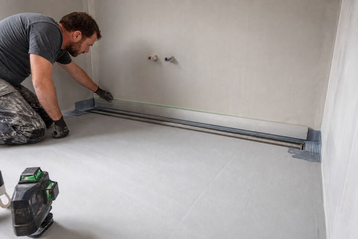 Caniveau de douche contre un mur : pente unique et raccord à la membrane